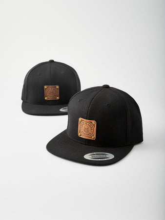 Snapback-Cap in Schwarz mit hellbraunem und dunkelbraunem Lederpatch